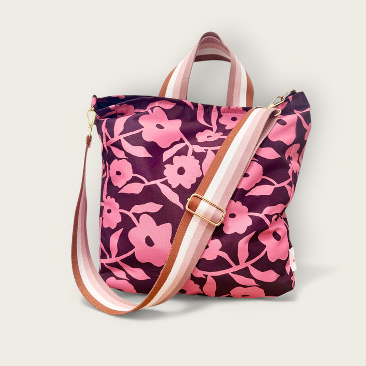 Pink floral patterned cross body bag with pink and beige stripped long sholuder strap and short handles